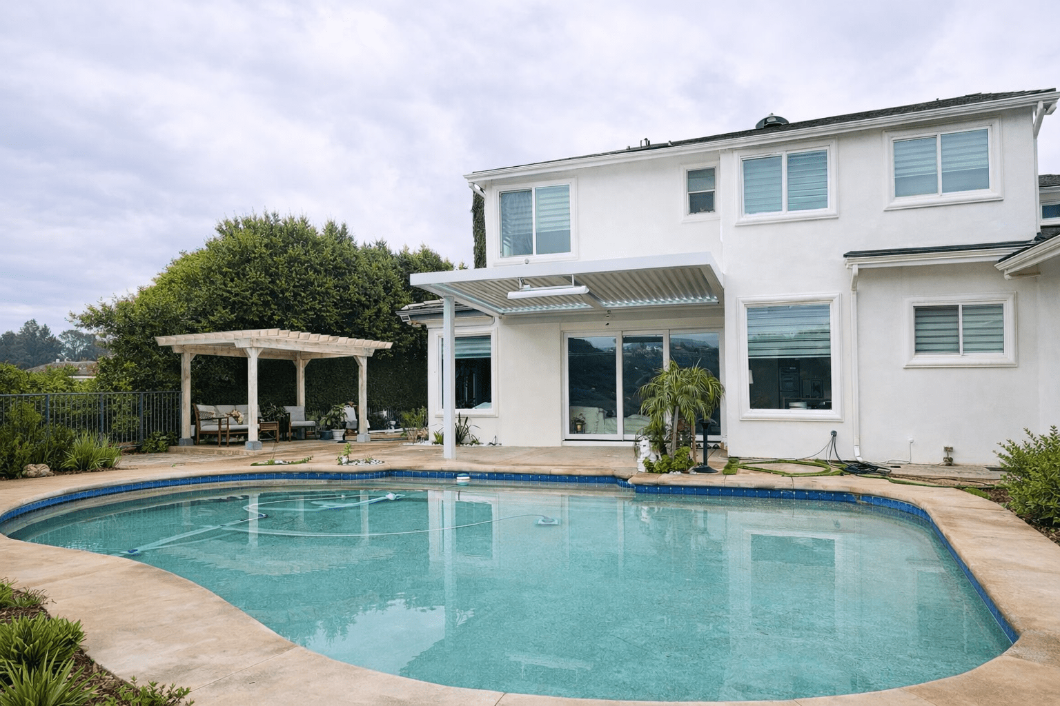Modern white house with a pool and pergola in the backyard.