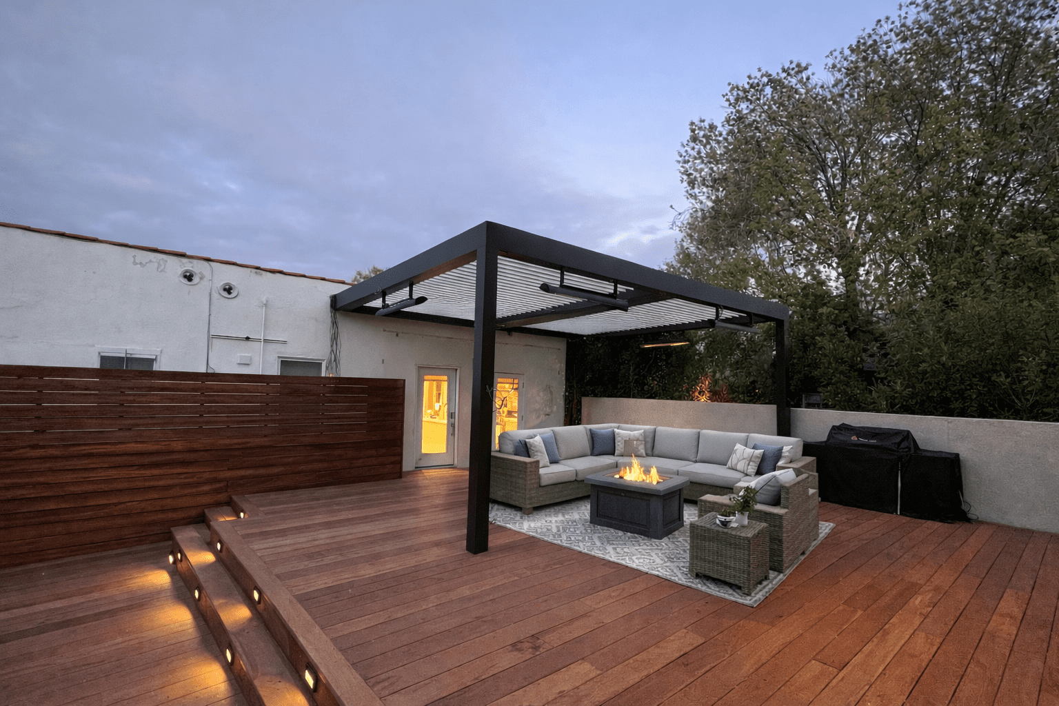 Modern outdoor patio with comfortable seating and fire pit under a pergola.