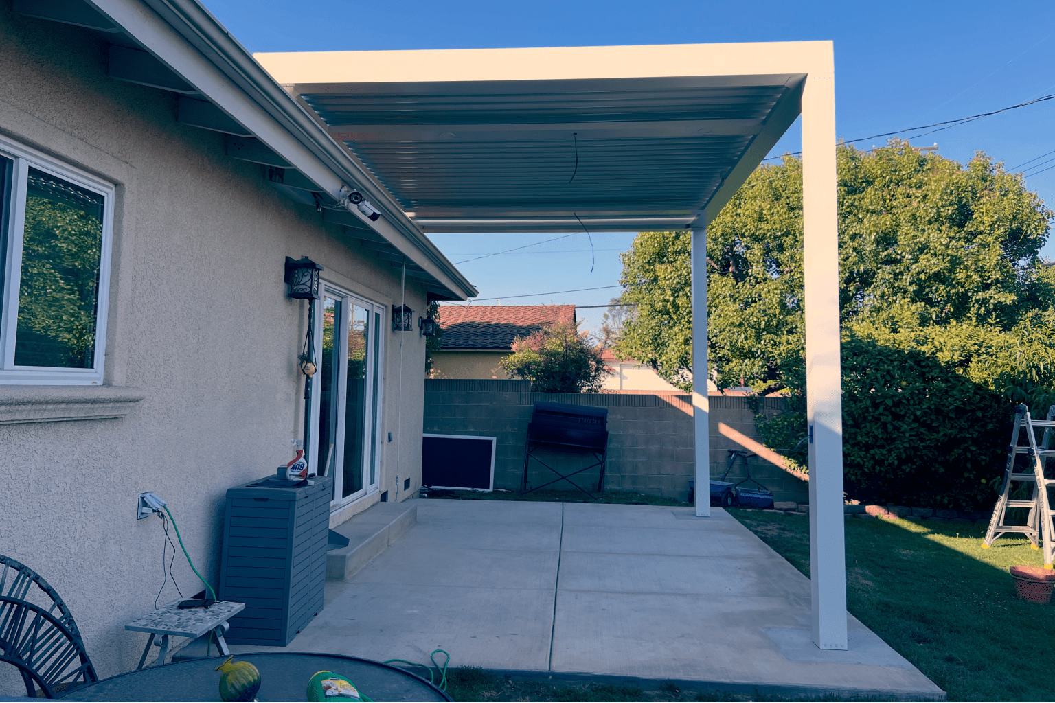 A backyard patio with a covered pergola and grill area.
