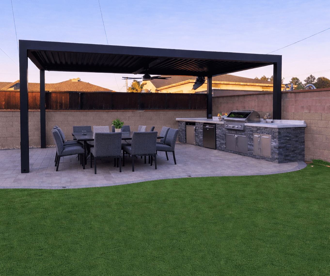 Modern backyard patio with outdoor dining and grill area under a pergola.